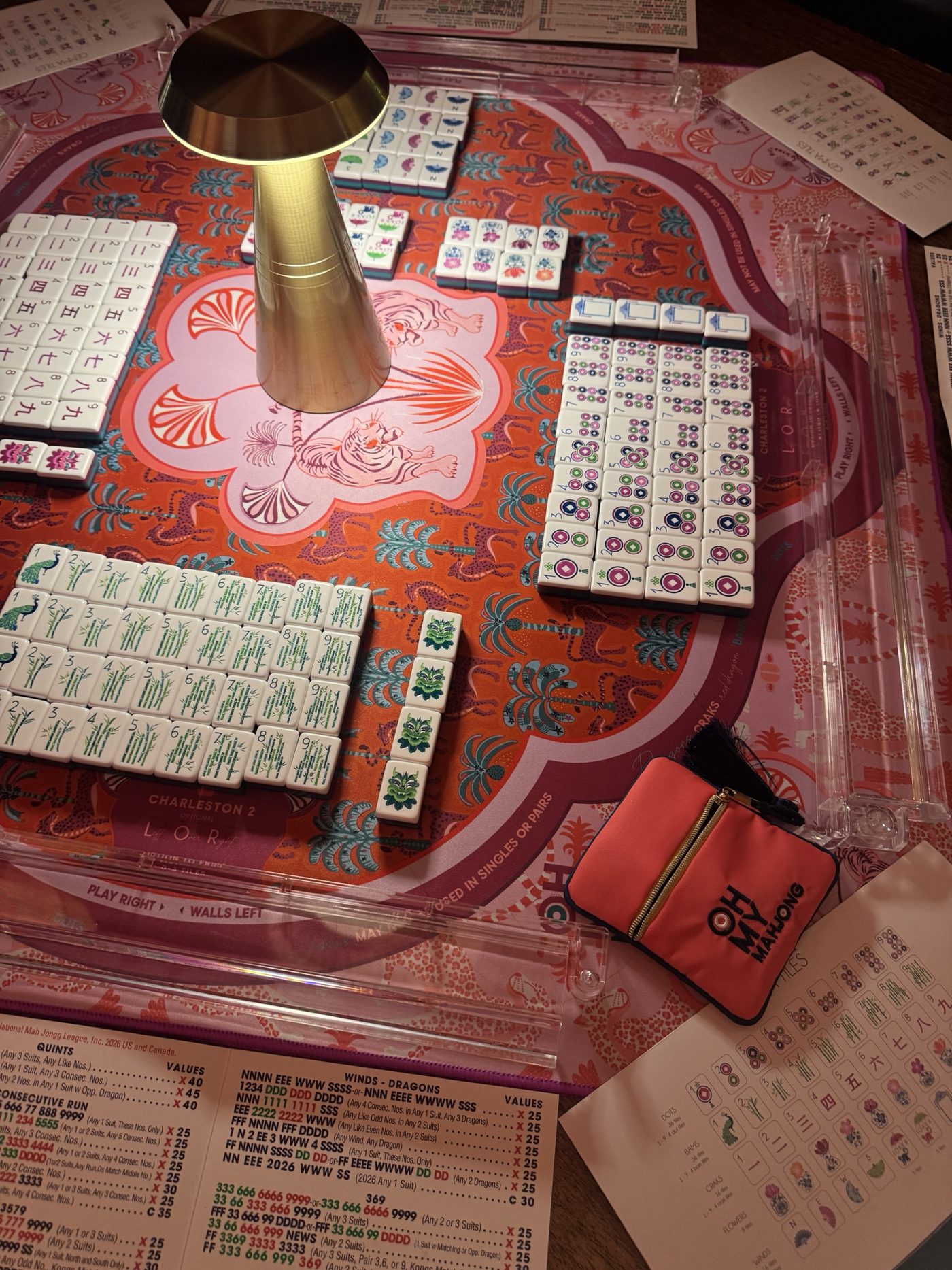 Tiles racked up on a pink and orange tiger-print mat with an Oh My Mahjong pouch
