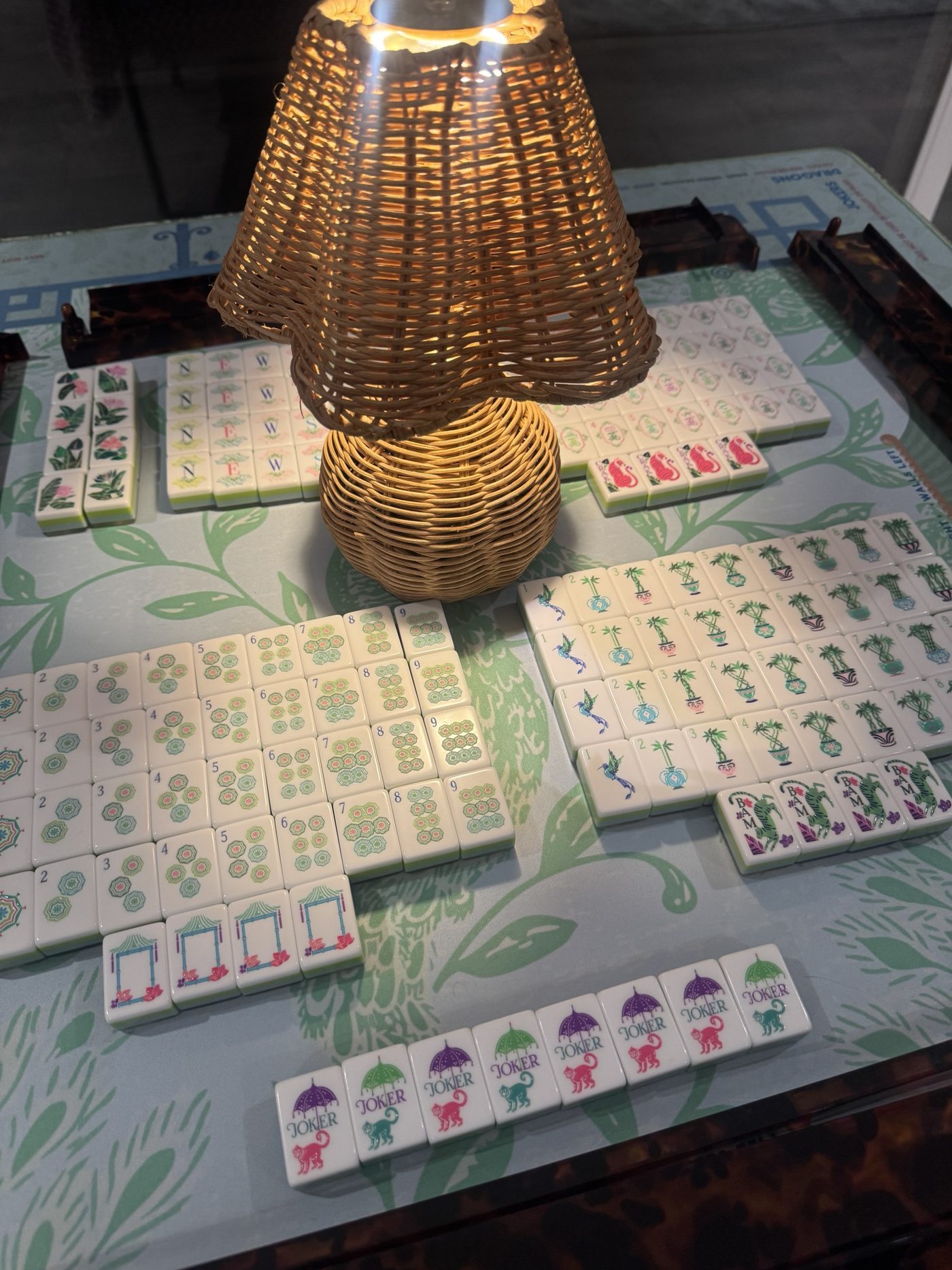 Jokers and flower tiles laid out beside a glowing wicker lamp